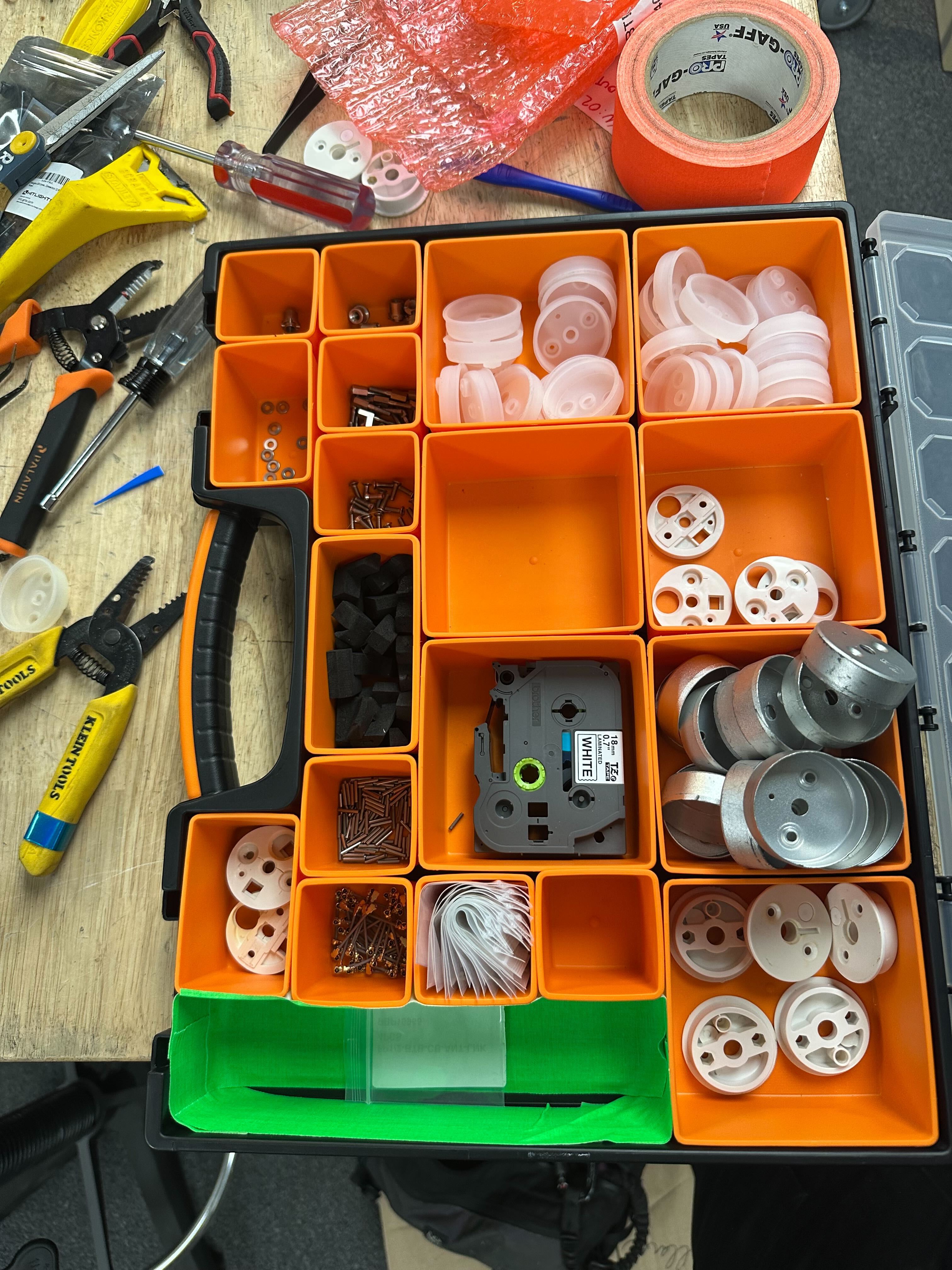 A tech's parts organizer tray at their workbench, holding small working quantities of various parts